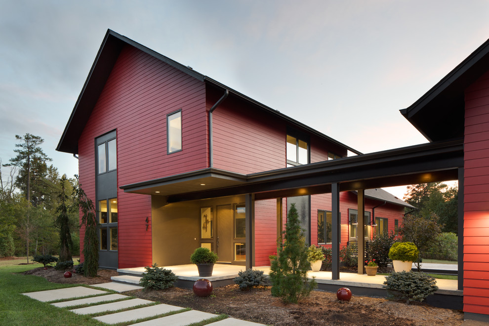 Mid-sized modern two-storey red house exterior with concrete fiberboard siding, a gable roof and a shingle roof.