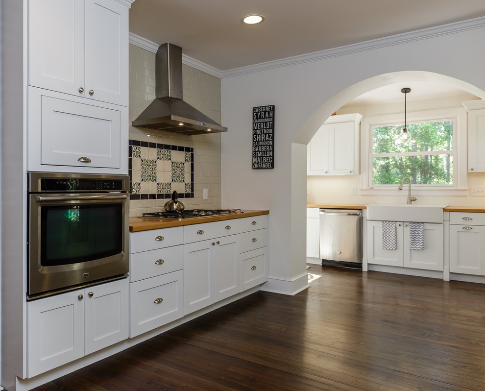 Large transitional l-shaped dark wood floor eat-in kitchen photo in Raleigh with shaker cabinets, white cabinets, stainless steel appliances, a farmhouse sink, beige backsplash, subway tile backsplash and no island