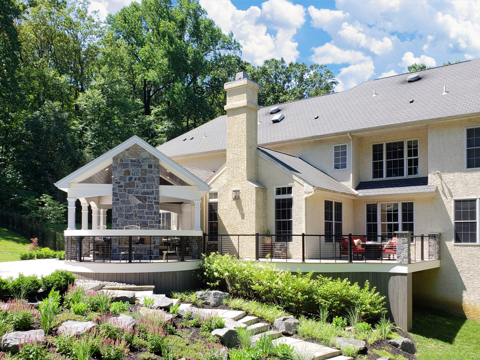 This is an example of a mid-sized transitional metal railing back porch design with a fireplace.