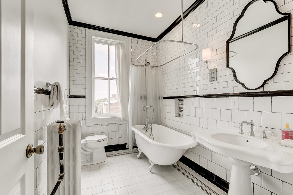 Photo of a transitional bathroom in Baltimore with a claw-foot tub, a shower/bathtub combo, black and white tile, subway tile, a pedestal sink, white floor, a shower curtain, a single vanity and a niche.