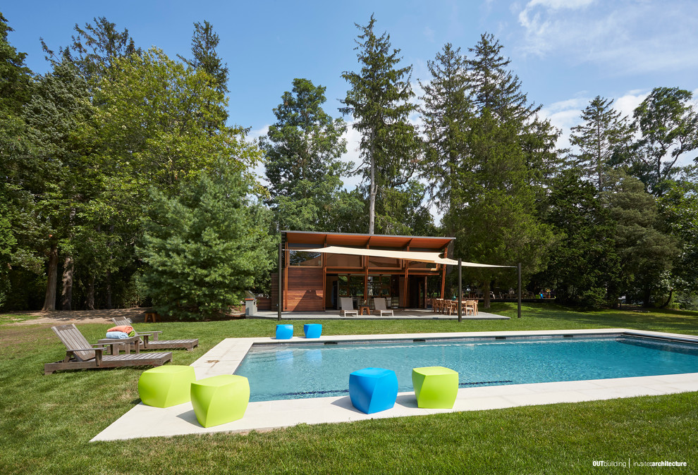 Photo of a small contemporary backyard rectangular pool in New York with a pool house and natural stone pavers.
