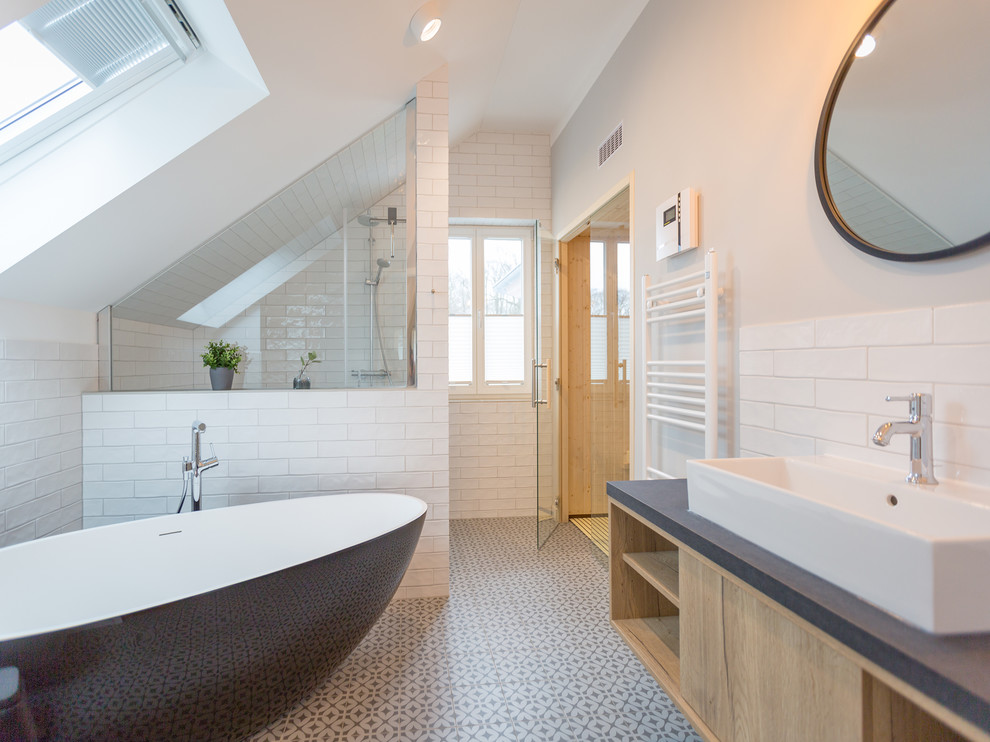 Photo of a large contemporary 3/4 wet room bathroom in Berlin with flat-panel cabinets, light wood cabinets, a freestanding tub, white tile, ceramic floors, a vessel sink, subway tile, an open shower, beige walls, white floor and grey benchtops.