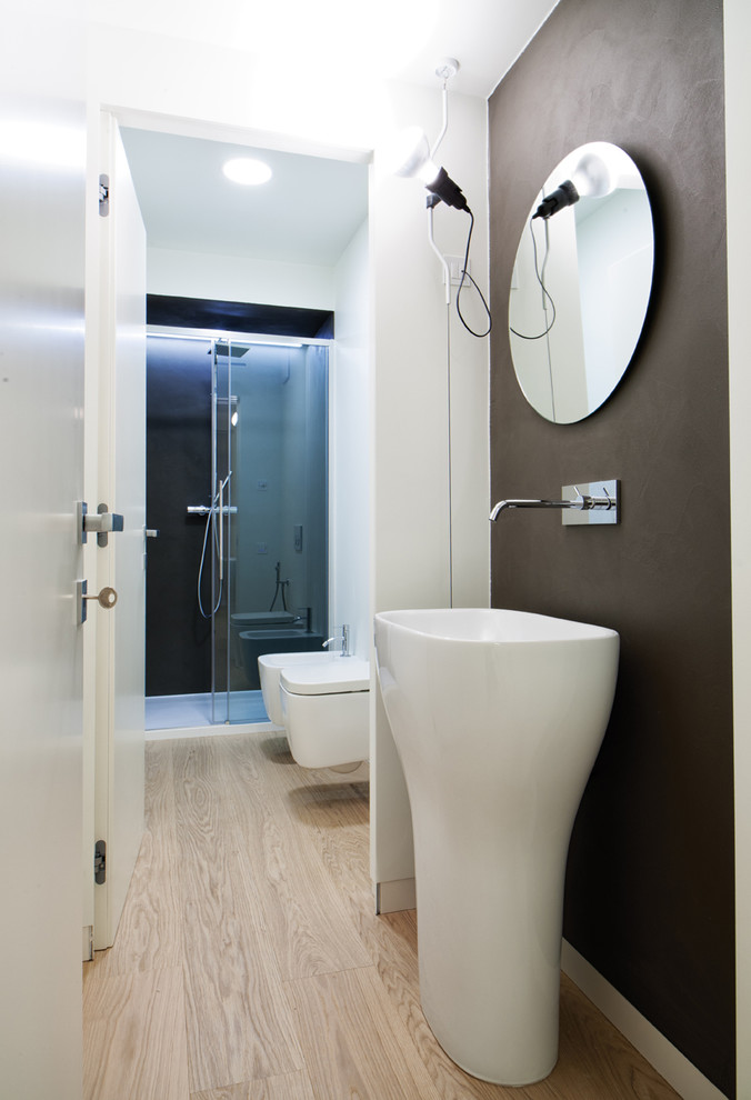 This is an example of a mid-sized contemporary bathroom in Other with a wall-mount toilet, light hardwood floors, a pedestal sink and beige floor.