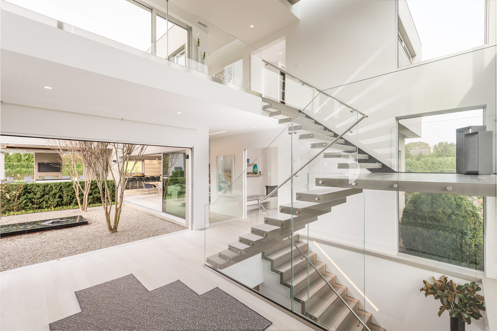 Expansive contemporary floating staircase in New York with open risers and glass railing.
