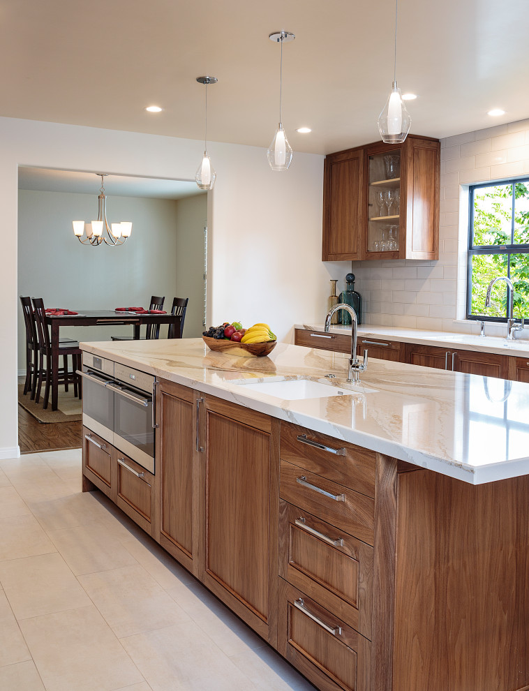 Inspiration for a mid-sized transitional open plan kitchen in Los Angeles with an undermount sink, recessed-panel cabinets, medium wood cabinets, quartz benchtops, white splashback, ceramic splashback, stainless steel appliances, with island, beige floor, white benchtop and limestone floors.