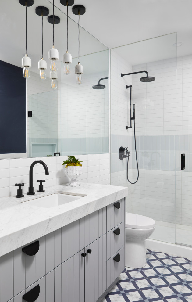 Photo of a small transitional bathroom in Toronto with flat-panel cabinets, grey cabinets, an alcove shower, white tile, an undermount sink, multi-coloured floor, white benchtops, a single vanity and a built-in vanity.