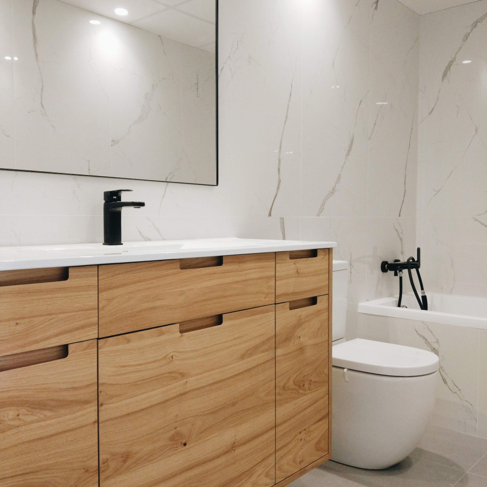 Design ideas for a mid-sized modern powder room with flat-panel cabinets, white cabinets, an urinal, gray tile, grey walls, porcelain floors, an integrated sink, engineered quartz benchtops and grey floor.