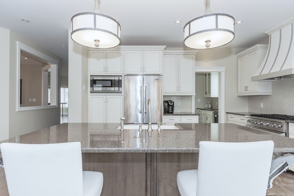 Kitchen - large transitional kitchen idea in Toronto with a farmhouse sink, white cabinets, quartz countertops, gray backsplash, ceramic backsplash, stainless steel appliances and an island