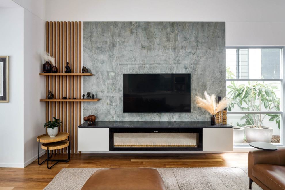 Cette photo montre un grand salon tendance ouvert avec un mur blanc, un sol en bois brun, une cheminée standard, un manteau de cheminée en pierre, un téléviseur fixé au mur et boiseries.