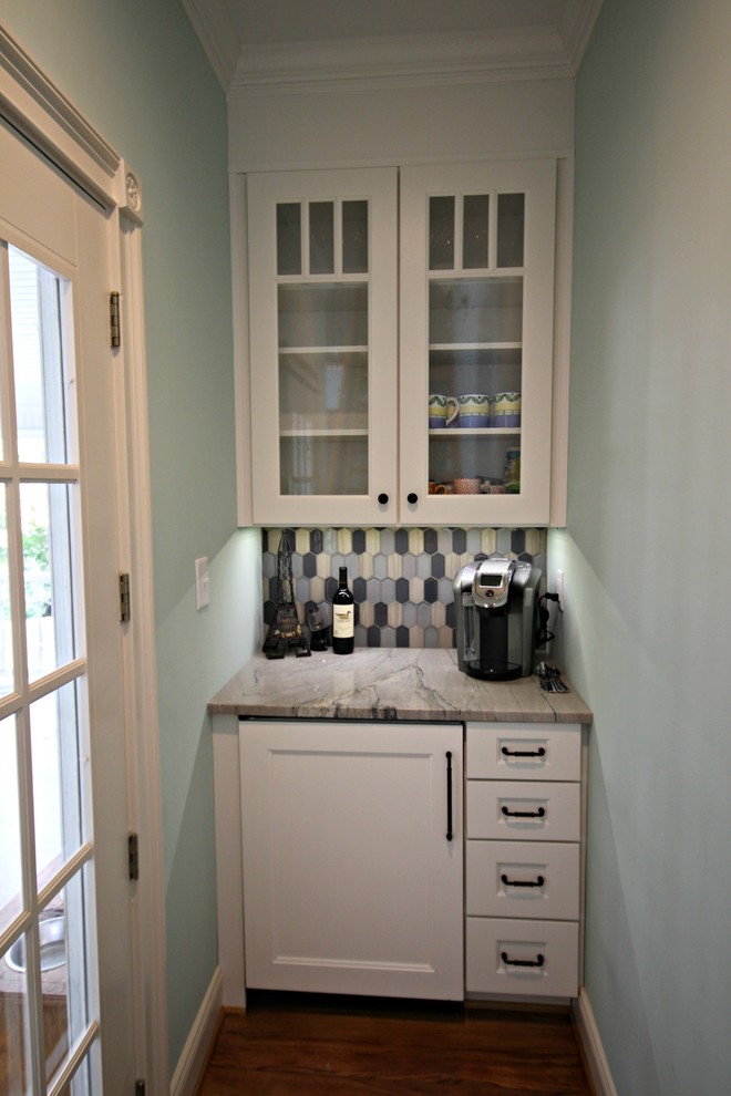 This is an example of a small country single-wall wet bar in Charlotte with no sink, recessed-panel cabinets, white cabinets, quartzite benchtops, blue splashback, ceramic splashback, medium hardwood floors and brown floor.