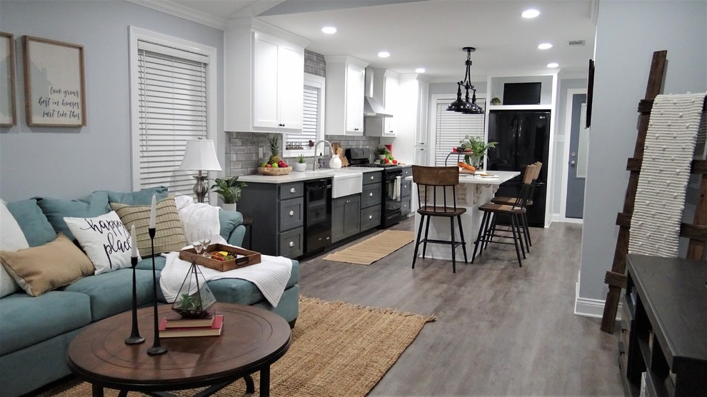 Small country l-shaped open plan kitchen in Other with a farmhouse sink, shaker cabinets, white cabinets, quartzite benchtops, grey splashback, subway tile splashback, black appliances, vinyl floors, with island, grey floor and white benchtop.