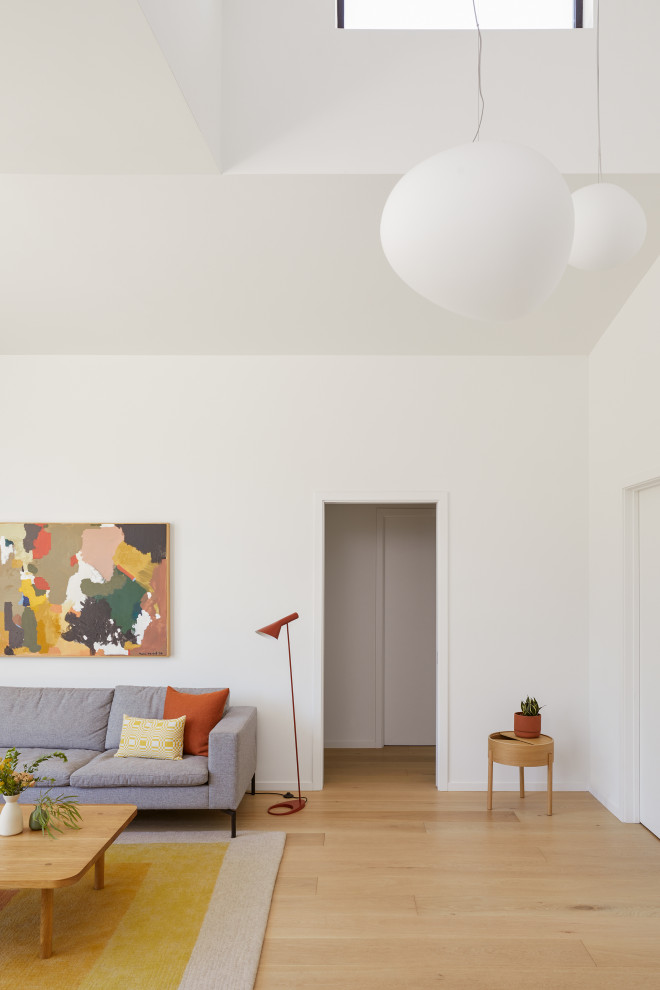 Стильный дизайн: изолированная комната для игр среднего размера в стиле модернизм с белыми стенами, светлым паркетным полом, телевизором на стене, коричневым полом и сводчатым потолком без камина - последний тренд