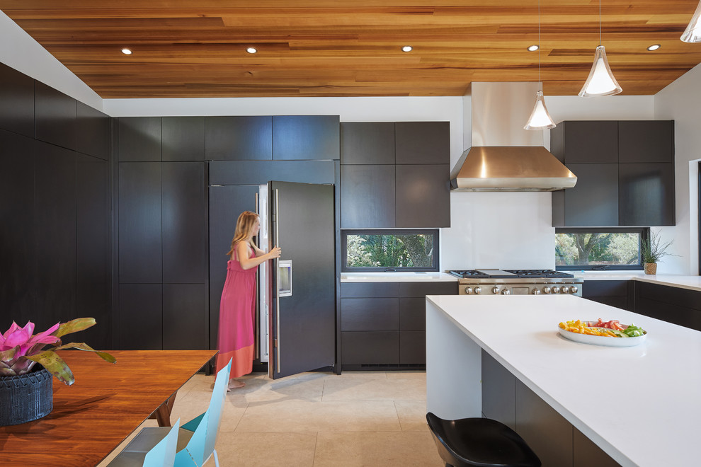 Inspiration for a midcentury eat-in kitchen in Austin with a drop-in sink, black cabinets, quartz benchtops, stainless steel appliances, ceramic floors, with island, grey floor and white benchtop.