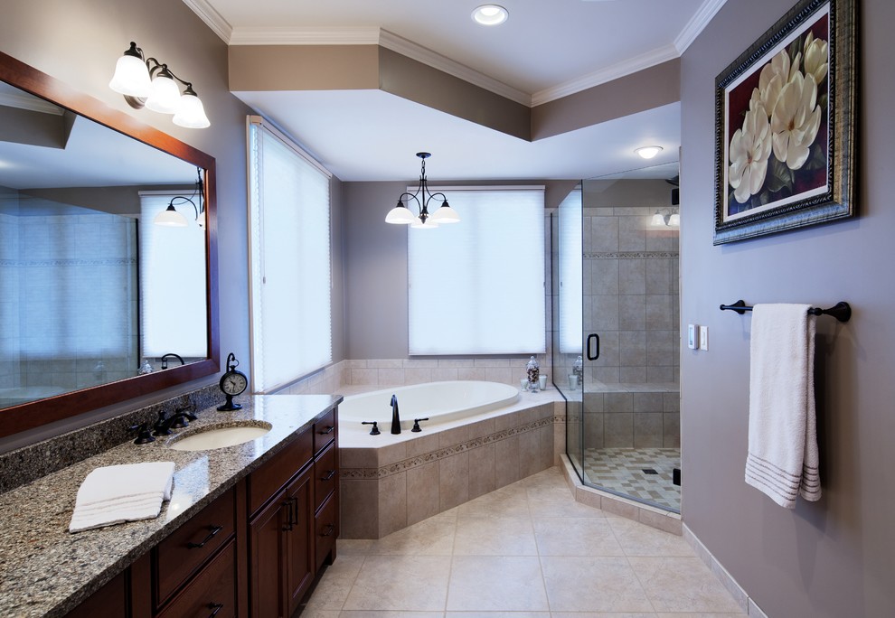Mid-sized traditional master bathroom in Detroit with an undermount sink, recessed-panel cabinets, dark wood cabinets, granite benchtops, a corner shower, beige tile, ceramic tile, grey walls, porcelain floors and a drop-in tub.