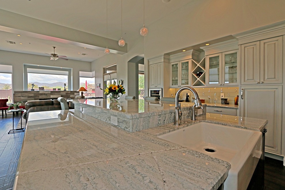 Open concept kitchen - large transitional dark wood floor open concept kitchen idea in Phoenix with a farmhouse sink, glass-front cabinets, white cabinets, granite countertops, multicolored backsplash, glass tile backsplash, paneled appliances and an island