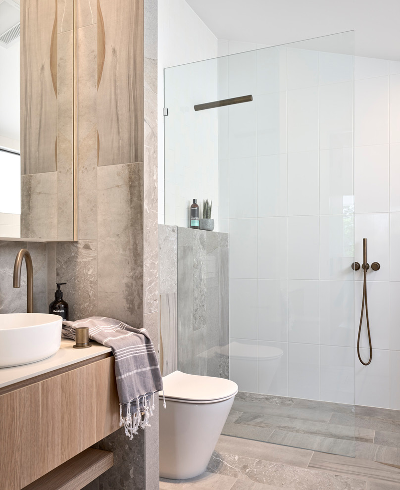 This is an example of a contemporary bathroom in Brisbane with flat-panel cabinets, light wood cabinets, a curbless shower, white tile, a vessel sink, grey floor, an open shower and white benchtops.