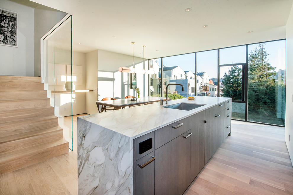 This is an example of a mid-sized modern l-shaped eat-in kitchen in San Francisco with an undermount sink, flat-panel cabinets, dark wood cabinets, marble benchtops, grey splashback, porcelain splashback, stainless steel appliances, dark hardwood floors, with island, brown floor and white benchtop.