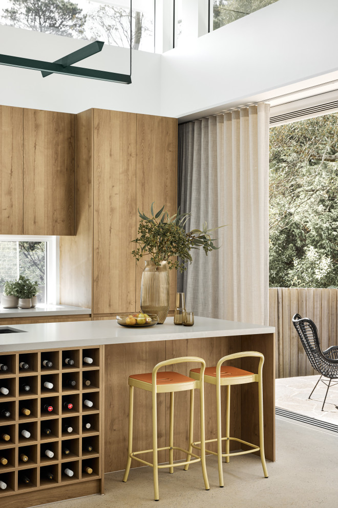 Design ideas for a mid-sized midcentury l-shaped eat-in kitchen in Sydney with an undermount sink, medium wood cabinets, quartz benchtops, glass sheet splashback, black appliances, concrete floors, with island, grey floor and grey benchtop.