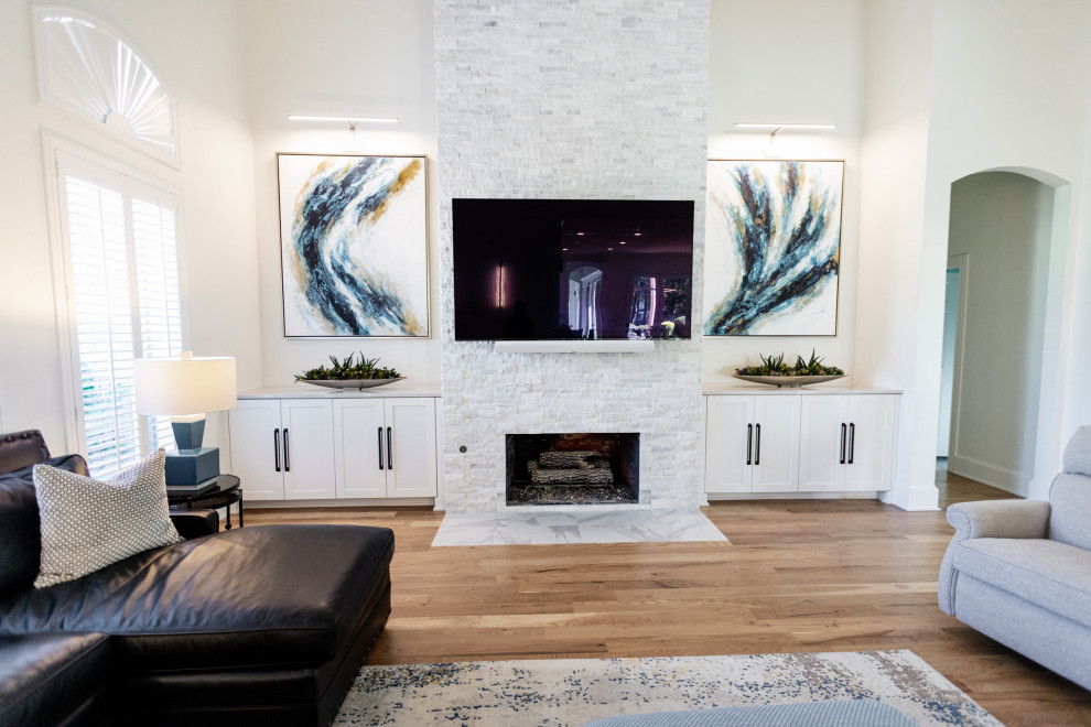Inspiration for a large modern open concept family room in Dallas with white walls, light hardwood floors, a standard fireplace, a wall-mounted tv and brown floor.