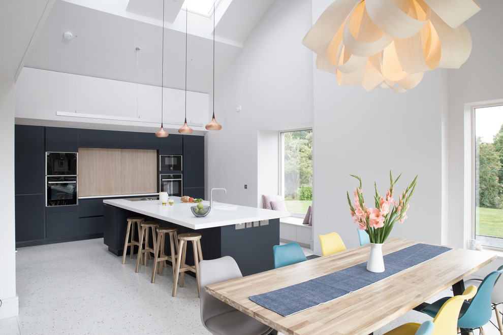 Large modern single-wall kitchen in Other with an integrated sink, blue cabinets, solid surface benchtops, black appliances, concrete floors, with island, grey floor and flat-panel cabinets.