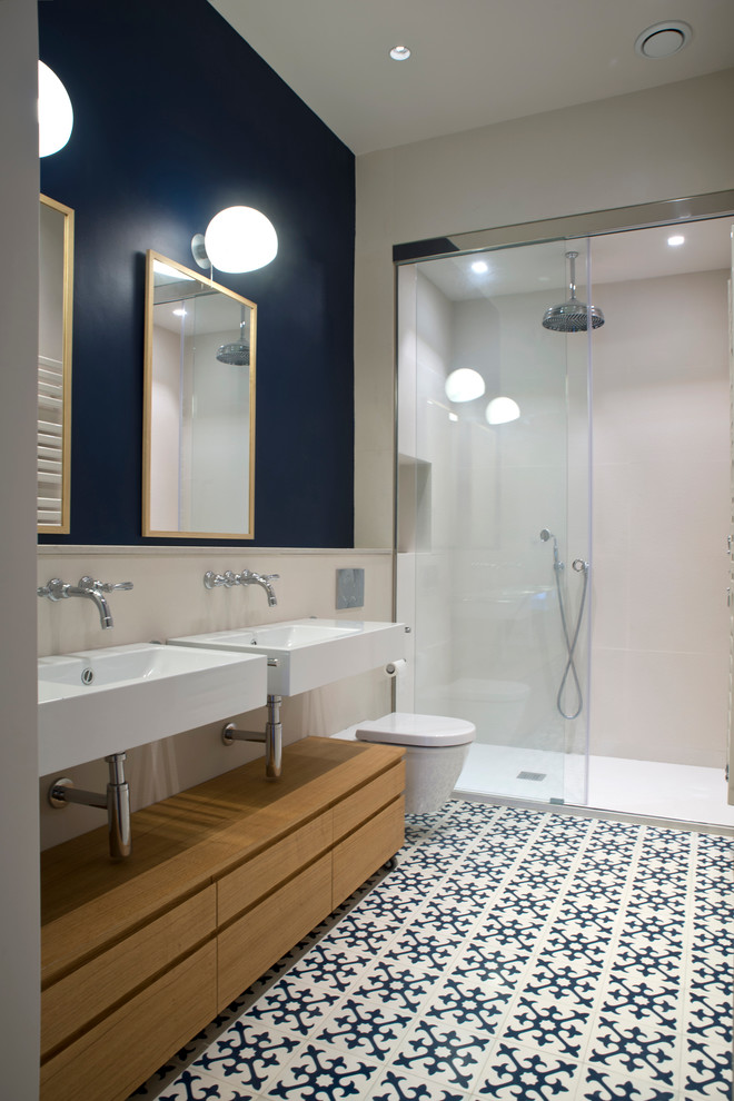 Inspiration for a mid-sized transitional 3/4 bathroom in Barcelona with flat-panel cabinets, medium wood cabinets, an alcove shower, a wall-mount toilet, multi-coloured walls, ceramic floors, a wall-mount sink and multi-coloured floor.