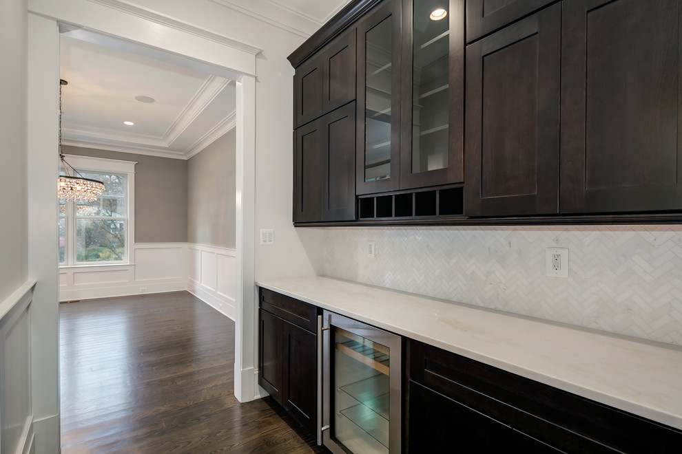 This is an example of a mid-sized transitional single-wall kitchen pantry in DC Metro with recessed-panel cabinets, dark wood cabinets, marble benchtops, white splashback, subway tile splashback, stainless steel appliances, dark hardwood floors and no island.