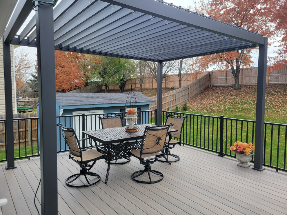 Large backyard ground level metal railing deck photo with a pergola