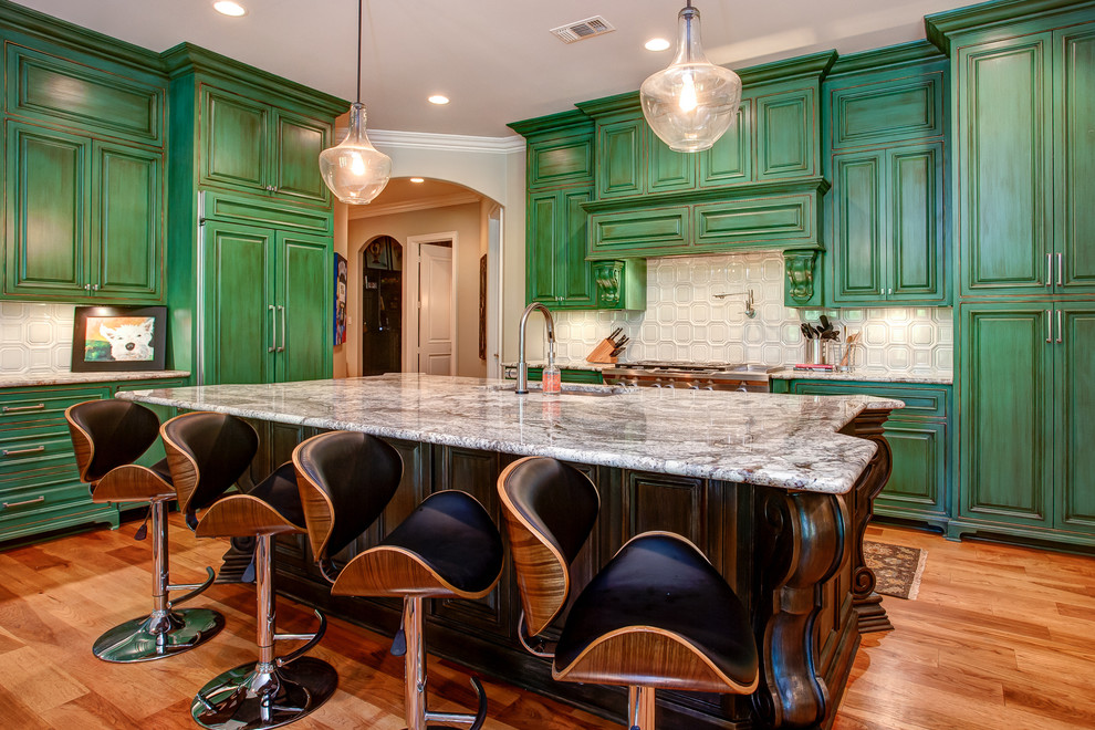 This is an example of a large eclectic l-shaped open plan kitchen in Little Rock with an undermount sink, raised-panel cabinets, green cabinets, marble benchtops, white splashback, glass tile splashback, stainless steel appliances, dark hardwood floors, with island and brown floor.