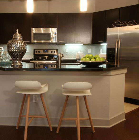 Inspiration for a small transitional l-shaped medium tone wood floor eat-in kitchen remodel in Houston with a double-bowl sink, flat-panel cabinets, brown cabinets, granite countertops, gray backsplash, ceramic backsplash, stainless steel appliances and an island