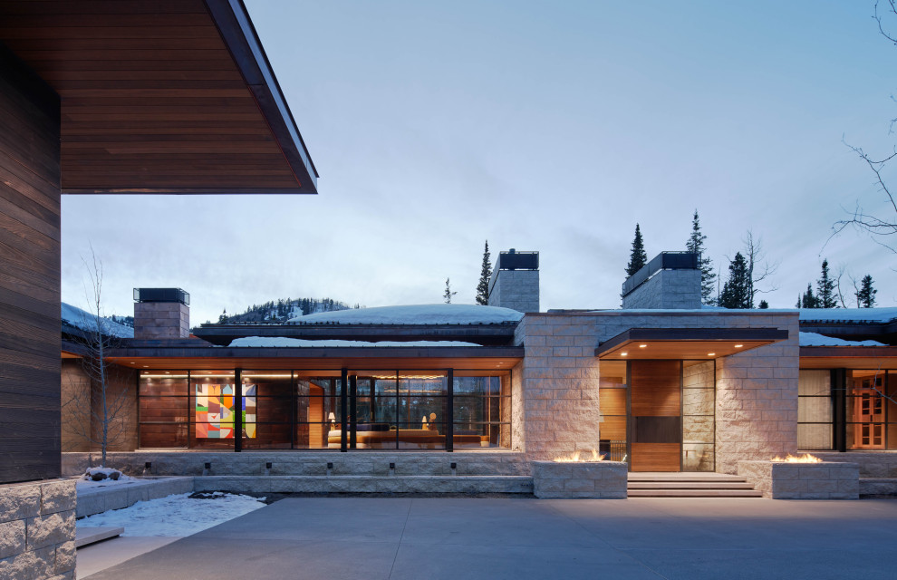 Expansive modern beige house exterior in Salt Lake City with four or more storeys, stone veneer, a hip roof, a metal roof and a brown roof.