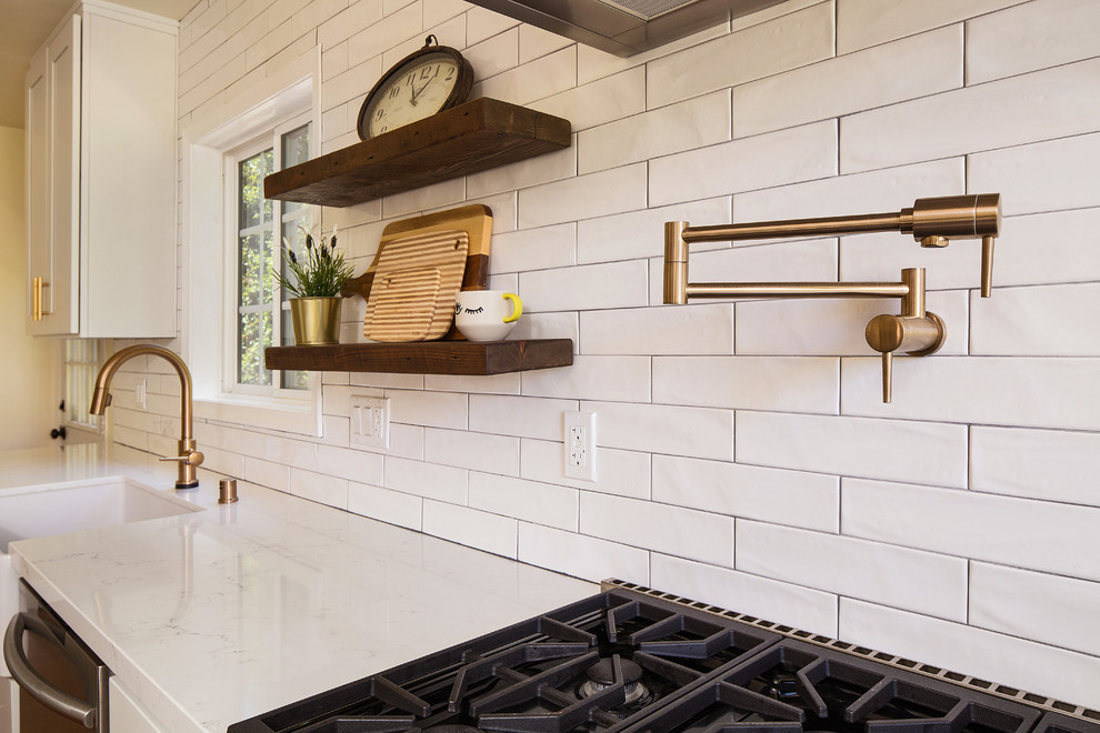 Mid-sized country single-wall open plan kitchen in Los Angeles with a farmhouse sink, shaker cabinets, white cabinets, quartz benchtops, white splashback, porcelain splashback, stainless steel appliances, light hardwood floors, with island, brown floor and yellow benchtop.