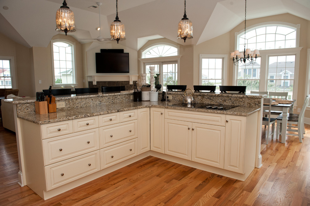 Example of a large transitional light wood floor open concept kitchen design with an undermount sink, raised-panel cabinets, beige cabinets, granite countertops, multicolored backsplash, mosaic tile backsplash, stainless steel appliances and a peninsula