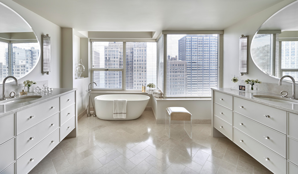 Photo of a large contemporary master bathroom in Chicago with beige walls, beige benchtops, a double vanity, flat-panel cabinets, white cabinets, a freestanding tub, a two-piece toilet, limestone floors, an undermount sink, granite benchtops, beige floor and a built-in vanity.