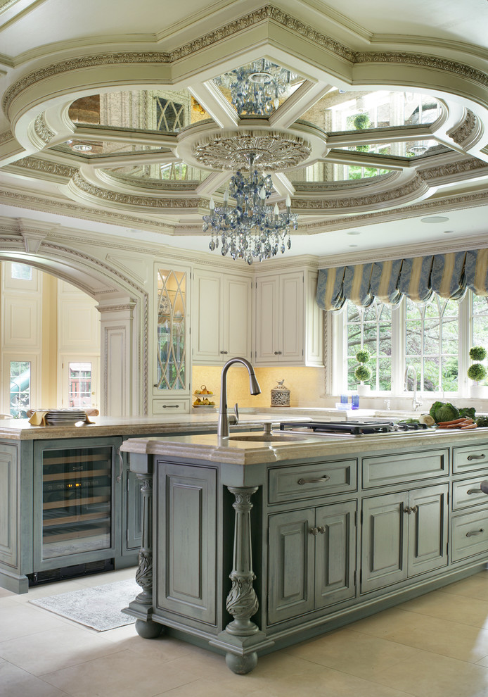 This is an example of a large traditional u-shaped eat-in kitchen in New York with a farmhouse sink, beaded inset cabinets, beige cabinets, limestone benchtops, beige splashback, mosaic tile splashback, coloured appliances, limestone floors and multiple islands.