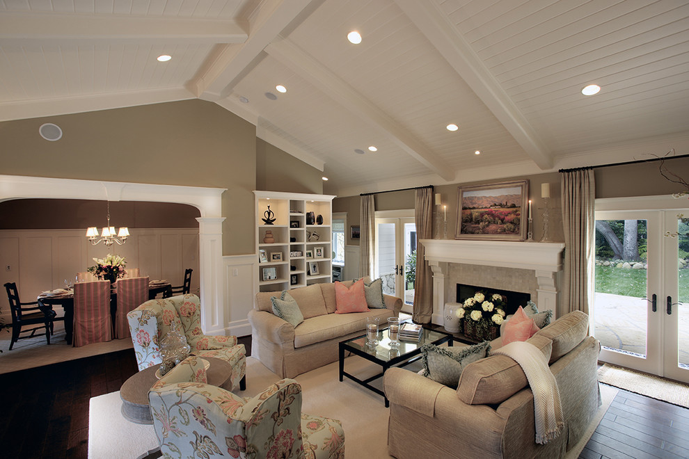 Photo of a large beach style formal open concept living room in Santa Barbara with beige walls, dark hardwood floors, a standard fireplace, a plaster fireplace surround, no tv and brown floor.