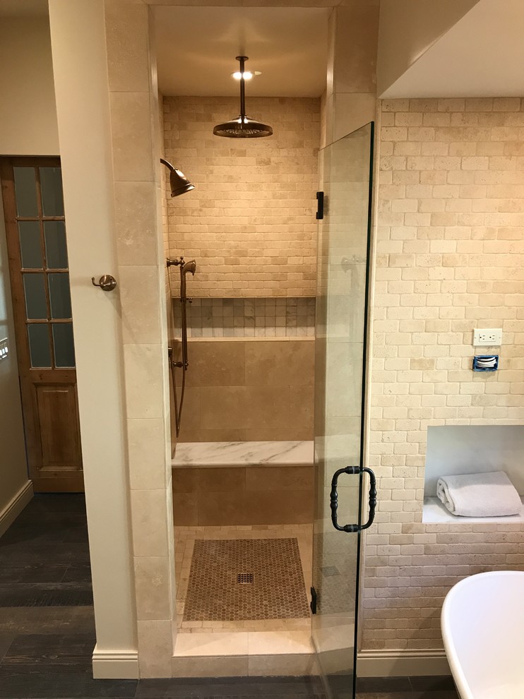 This is an example of a mid-sized mediterranean master bathroom in Phoenix with raised-panel cabinets, dark wood cabinets, a freestanding tub, an alcove shower, a one-piece toilet, beige tile, stone tile, beige walls, dark hardwood floors, a vessel sink, marble benchtops, brown floor and a hinged shower door.