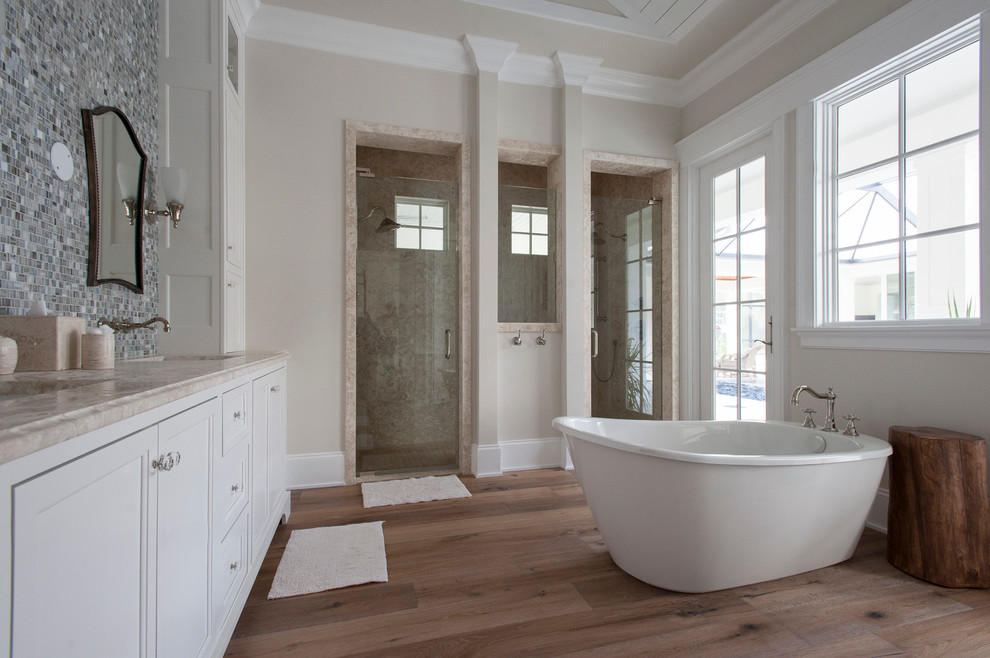 Design ideas for a large contemporary master bathroom in Jacksonville with an undermount sink, beaded inset cabinets, white cabinets, marble benchtops, a freestanding tub, a double shower, multi-coloured tile, stone tile, beige walls and medium hardwood floors.