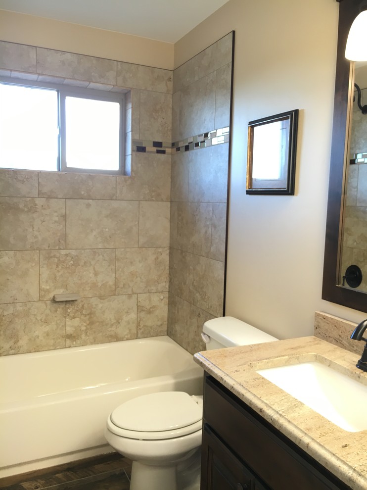 Mid-sized transitional kids' beige tile and porcelain tile porcelain tile alcove bathtub photo with raised-panel cabinets, dark wood cabinets, a two-piece toilet, beige walls, an undermount sink and granite countertops