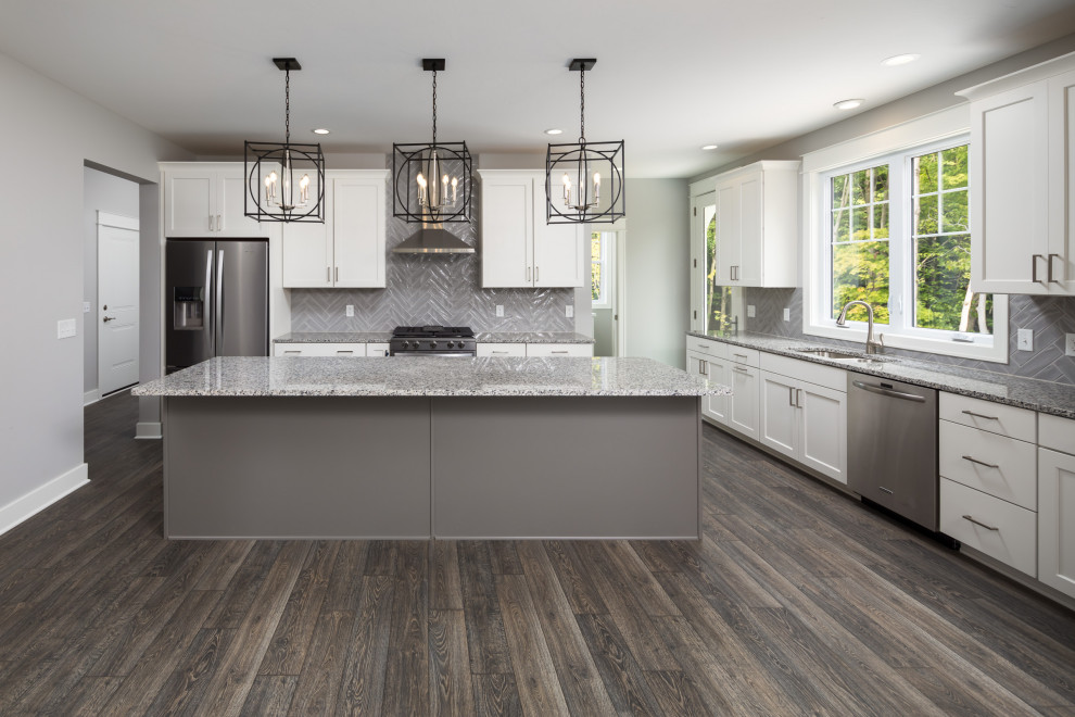 Mid-sized arts and crafts l-shaped eat-in kitchen in Grand Rapids with an undermount sink, recessed-panel cabinets, white cabinets, quartz benchtops, grey splashback, subway tile splashback, stainless steel appliances, vinyl floors, with island, brown floor and multi-coloured benchtop.