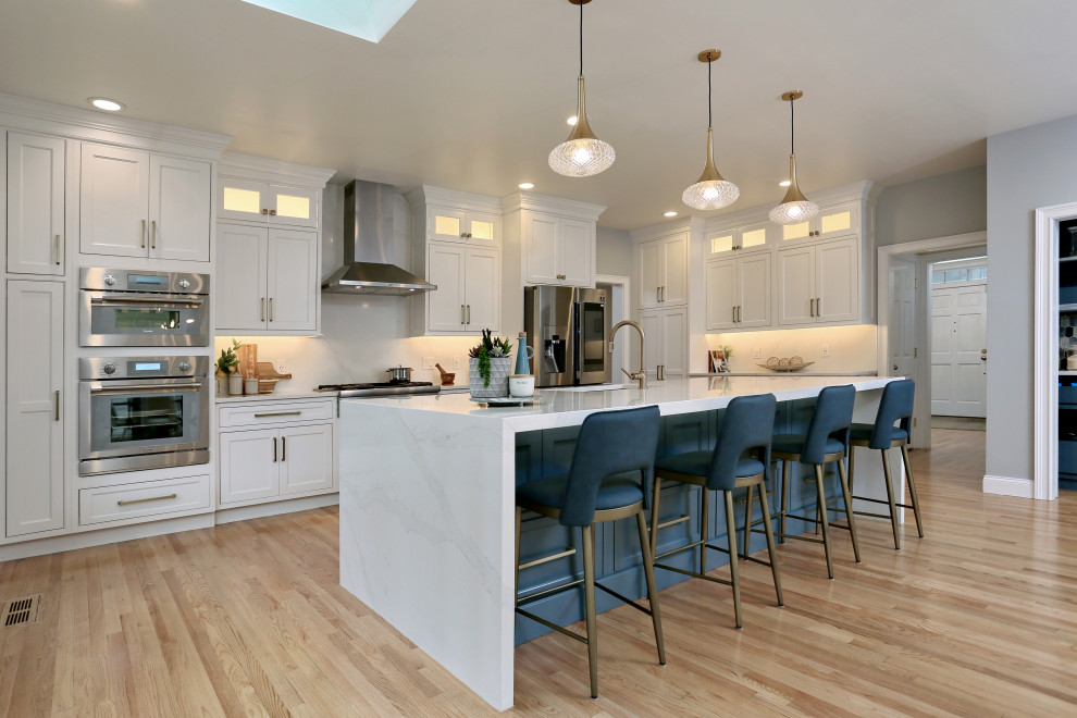 Design ideas for an expansive transitional u-shaped eat-in kitchen in Boston with an undermount sink, beaded inset cabinets, white cabinets, quartz benchtops, white splashback, engineered quartz splashback, stainless steel appliances, medium hardwood floors, with island and white benchtop.