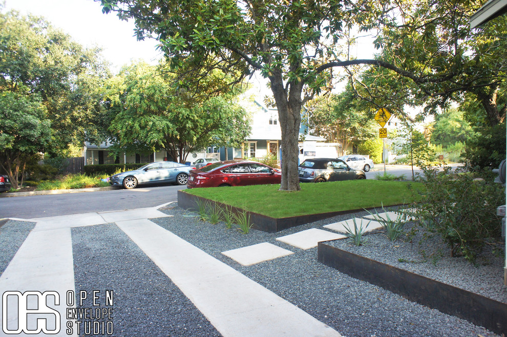 Photo of a small modern front yard driveway in Austin with a retaining wall and gravel.