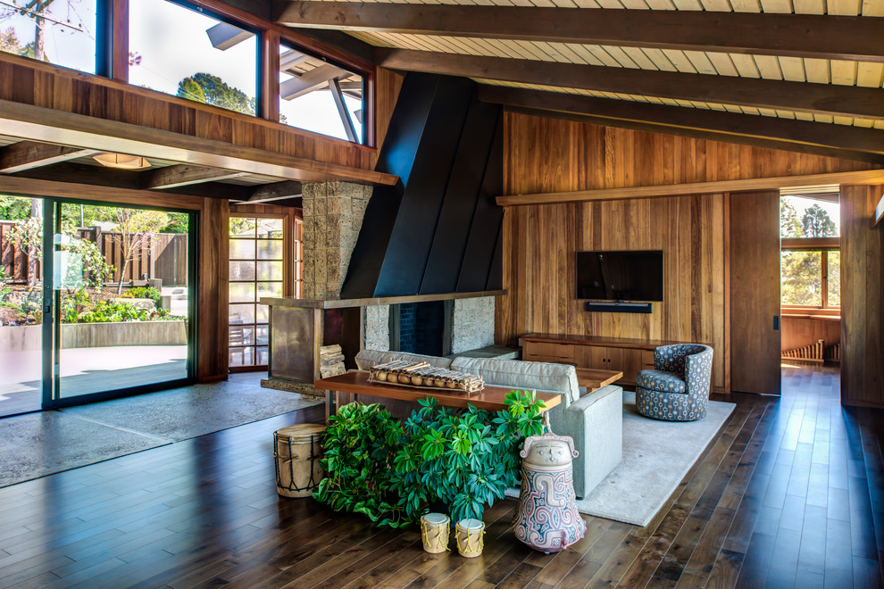 Inspiration for a mid-sized mid-century modern open concept dark wood floor and brown floor family room remodel in San Francisco with brown walls, a standard fireplace, a stone fireplace and a wall-mounted tv
