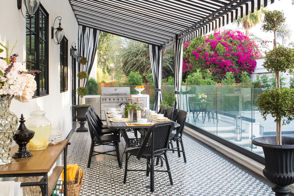 Inspiration for a large transitional backyard patio in Los Angeles with an outdoor kitchen, tile and an awning.