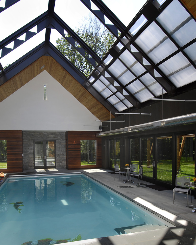 Large contemporary indoor rectangular pool in New York with a pool house and concrete slab.