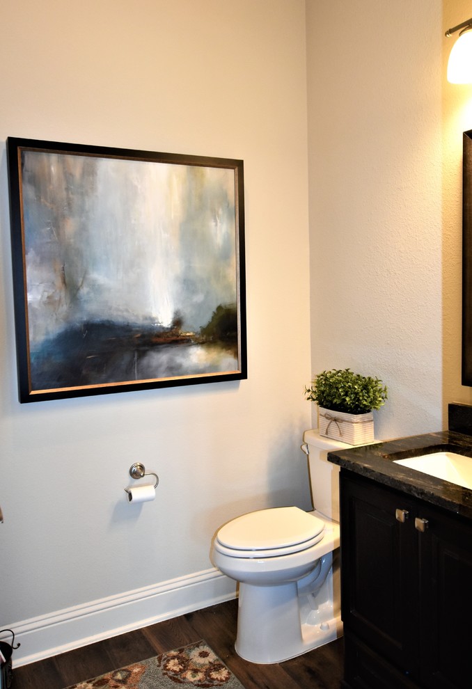 This is an example of a small transitional powder room in Houston with shaker cabinets, dark wood cabinets, a two-piece toilet, beige walls, medium hardwood floors, an undermount sink, granite benchtops, brown floor and multi-coloured benchtops.