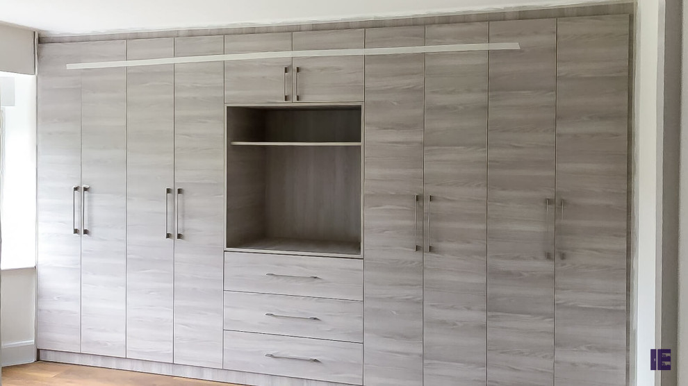 Design ideas for a large asian storage and wardrobe in London with flat-panel cabinets and medium wood cabinets.