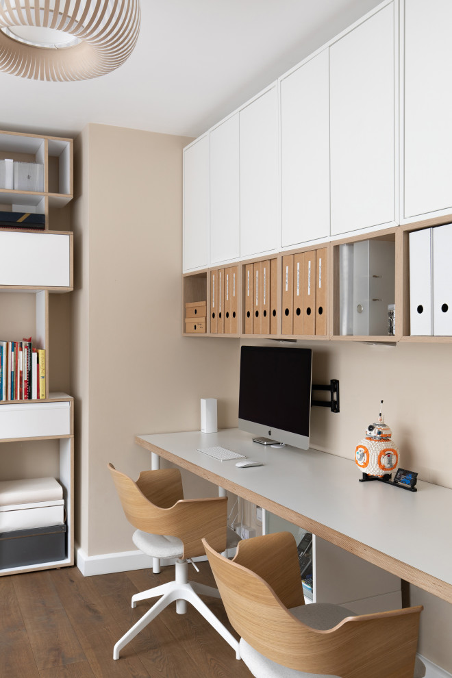 Mittelgroßes Modernes Arbeitszimmer mit Arbeitsplatz, beiger Wandfarbe, braunem Holzboden, freistehendem Schreibtisch und beigem Boden in Sussex