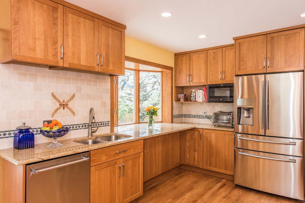 Inspiration for a large arts and crafts u-shaped open plan kitchen in DC Metro with an undermount sink, recessed-panel cabinets, brown cabinets, granite benchtops, beige splashback, terra-cotta splashback, stainless steel appliances, light hardwood floors and brown floor.