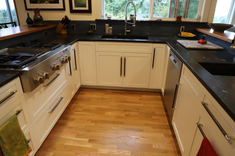 Inspiration for a mid-sized transitional u-shaped medium tone wood floor and brown floor eat-in kitchen remodel with shaker cabinets, white cabinets, granite countertops, blue backsplash, stainless steel appliances, black countertops, an undermount sink, stone tile backsplash and a peninsula