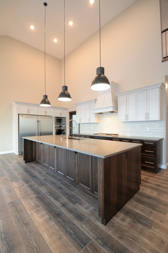 Photo of a mid-sized country single-wall open plan kitchen in Calgary with an undermount sink, recessed-panel cabinets, black cabinets, concrete benchtops, white splashback, matchstick tile splashback, stainless steel appliances, dark hardwood floors, with island and brown floor.